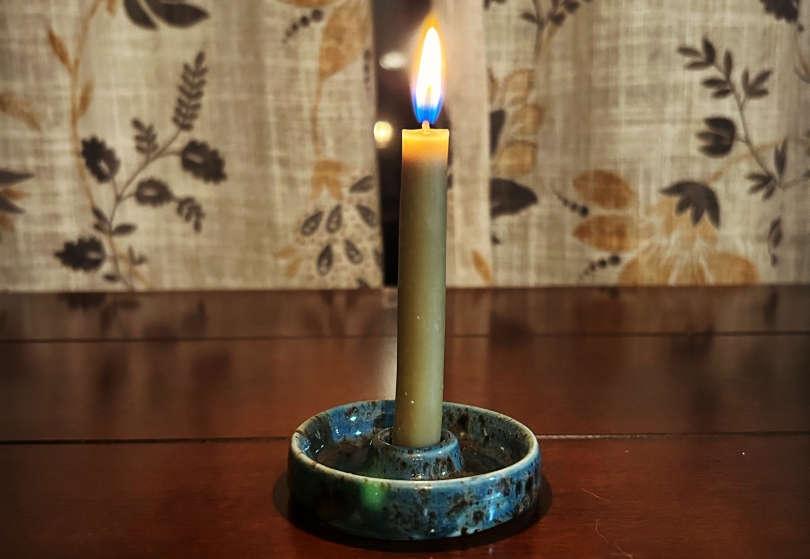 A bayberry candle burning in a ceramic holder